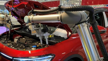 Zwei Cobots von Universal Robots arbeiten an der Montage eines roten Autos.